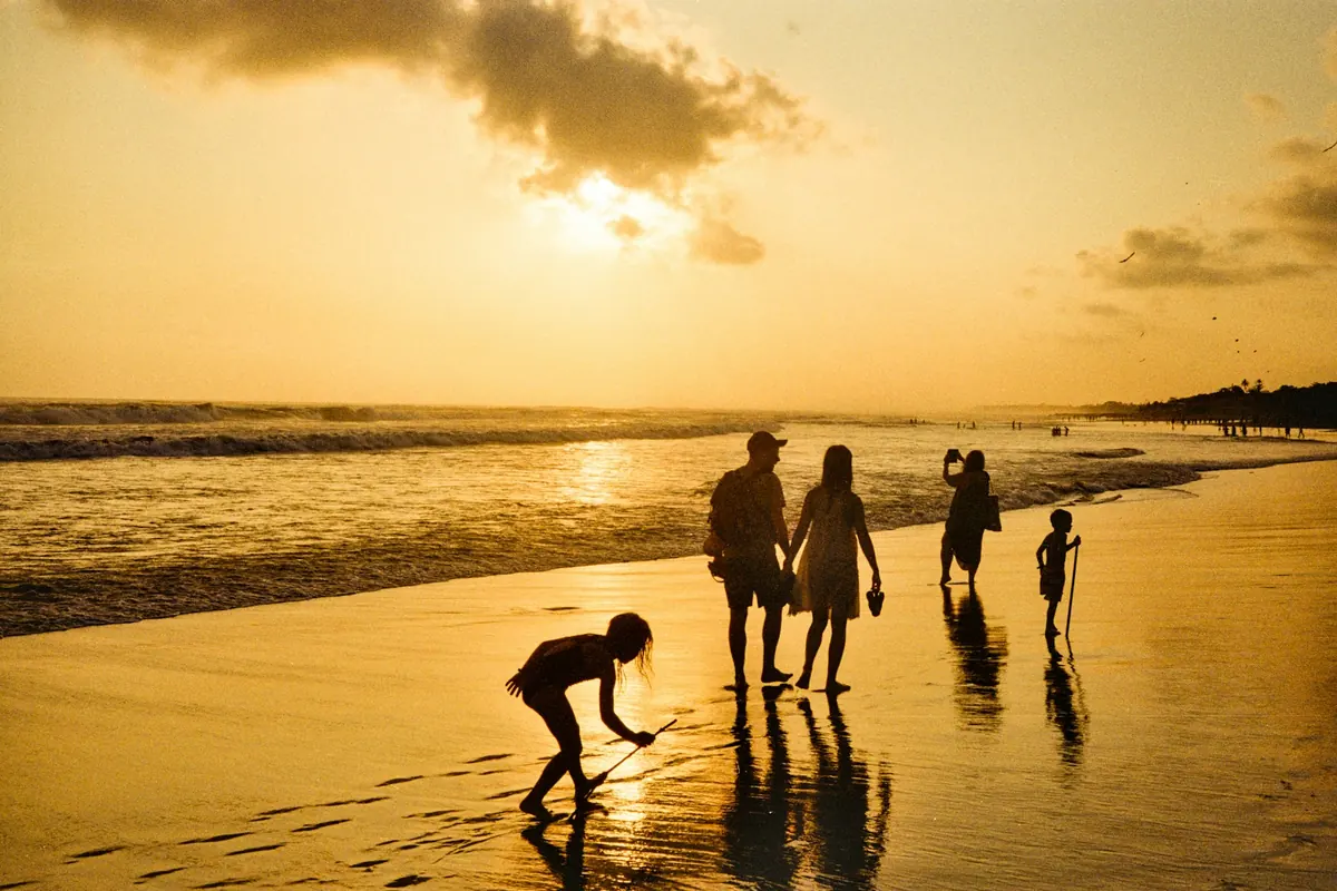 A family walking together along the shoreline at sunset