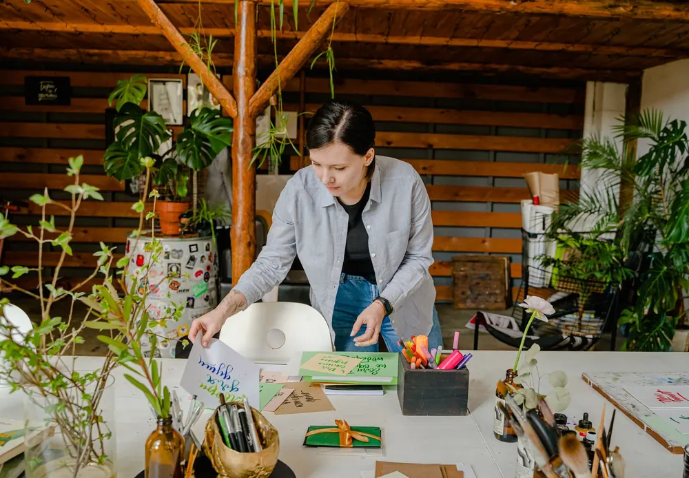 A designer sorting artwork at a sunlit studio table